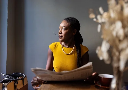 Female sitting at a table with a newspaper in her hand Female sitting at a table with a newspaper in her hand